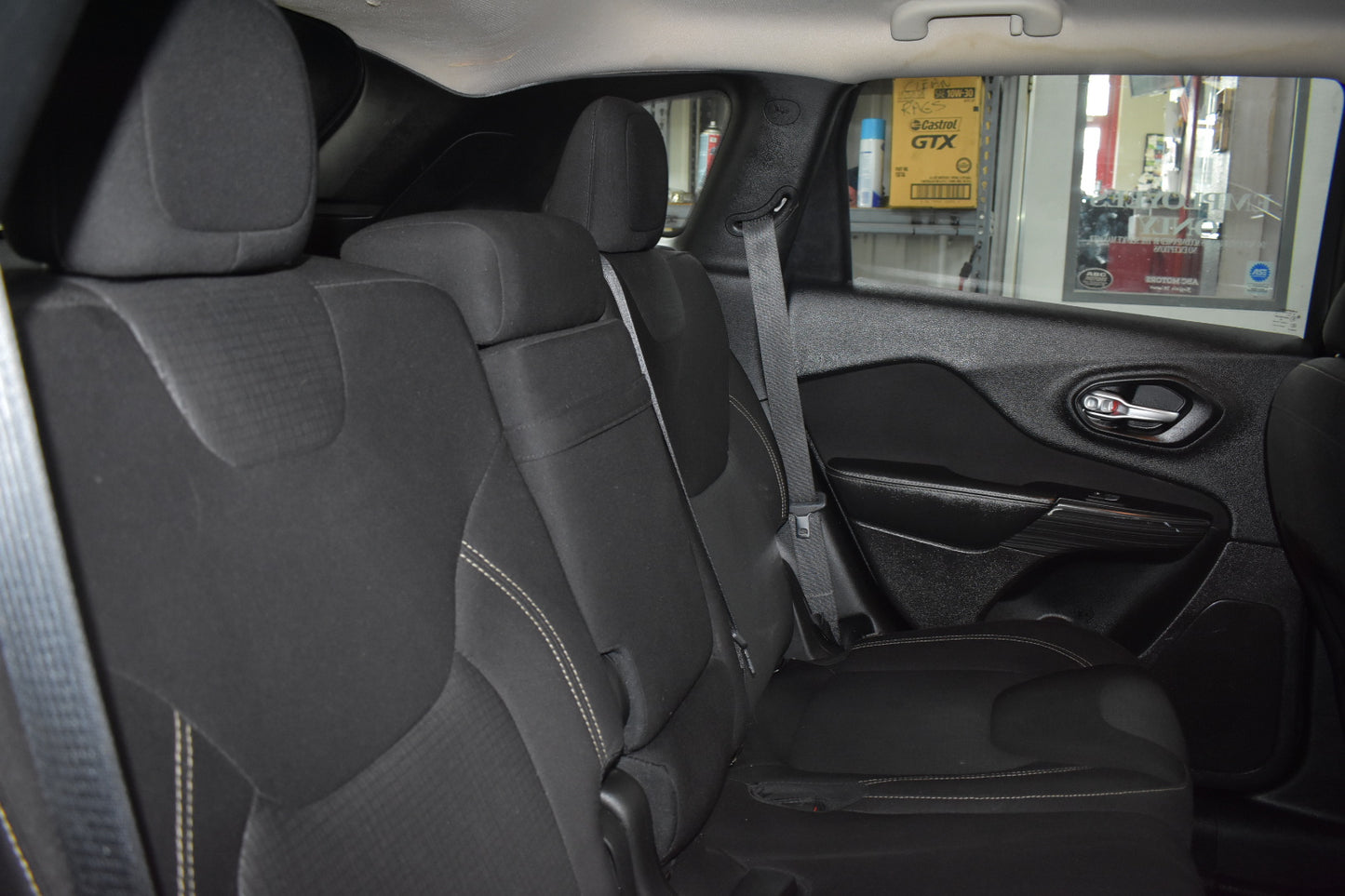 Car interior with gray seats and a view of a store exterior through the window.