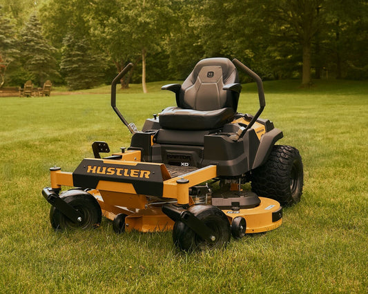 Mower on a grassy field with trees in the background