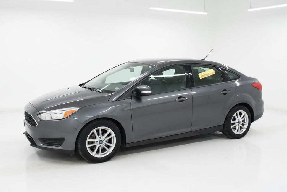 Gray car parked in front of a car dealership with a wreath on the door.
