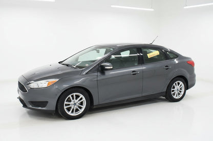 Gray car parked in front of a car dealership with a wreath on the door.