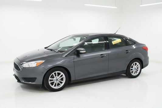 Gray car parked in front of a car dealership with a wreath on the door.