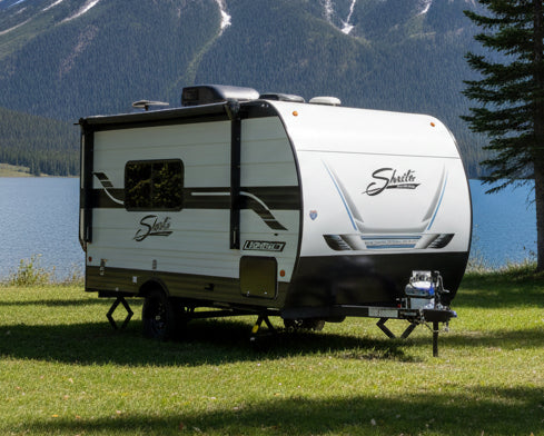 Shasta travel trailer parked on grass with trees in the background