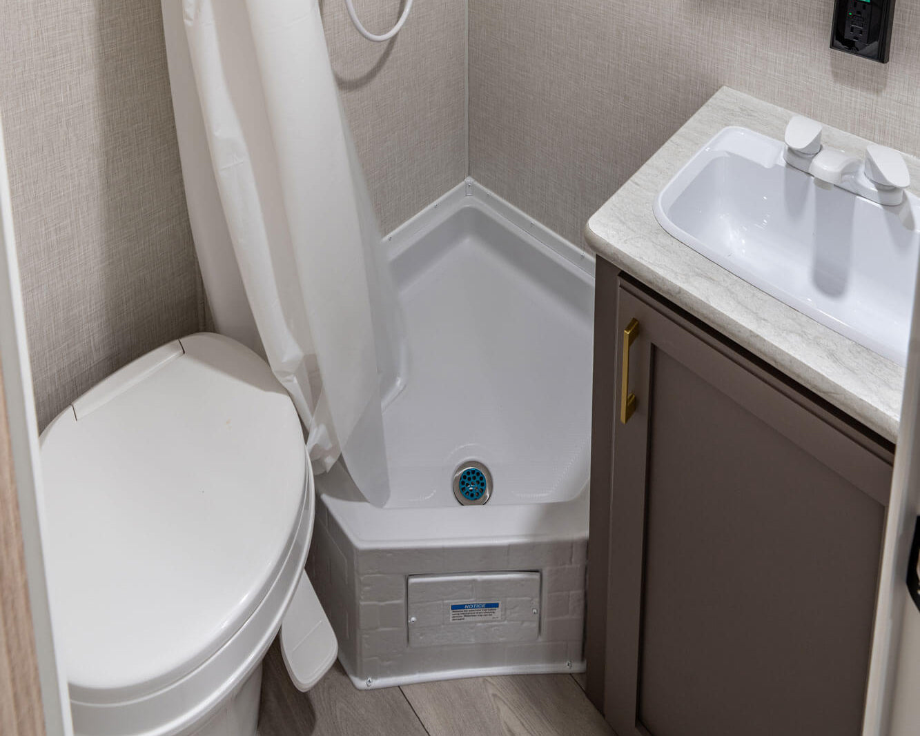 Compact bathroom with shower, toilet, sink, and mirror in a small space.