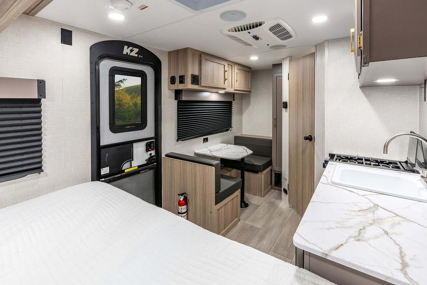 Interior of a modern RV with kitchen, bedroom, and living area.