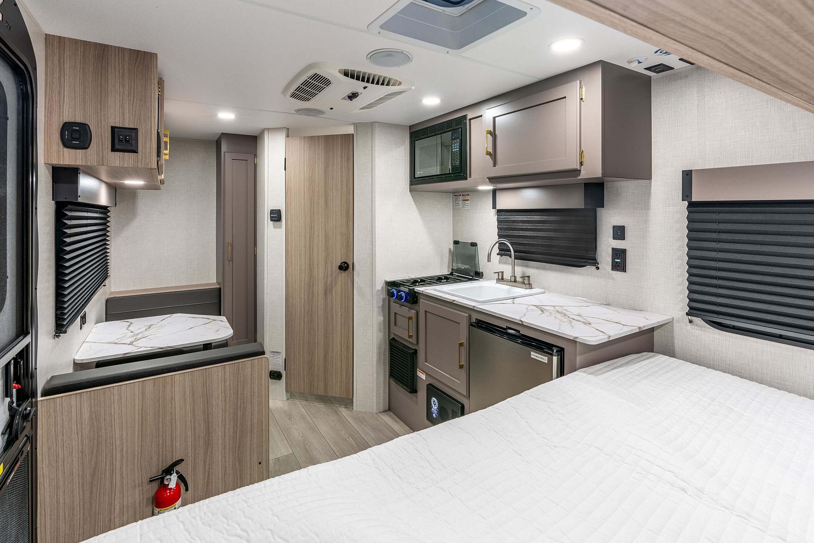 Interior of a modern RV with kitchen and bedroom setup