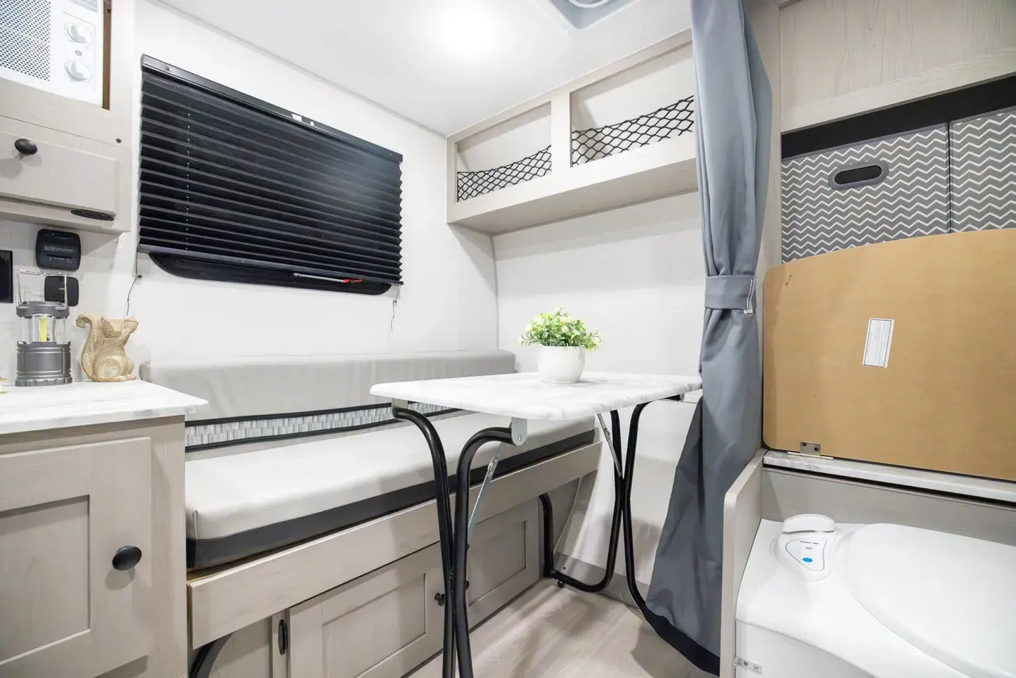 Compact living space with a bed, table, and storage compartments in a small room.