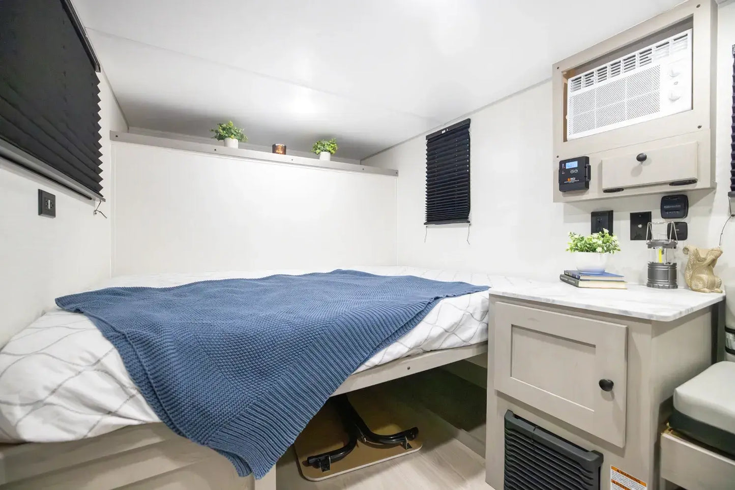 Compact living space with a bed, small kitchenette, and storage area.