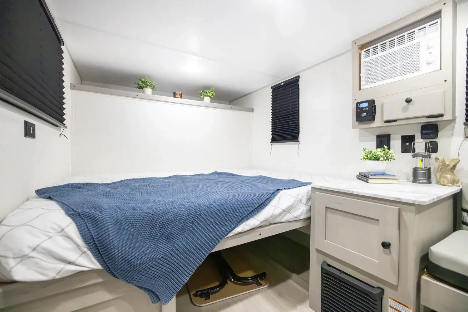 Compact living space with a bed, small kitchenette, and storage area.