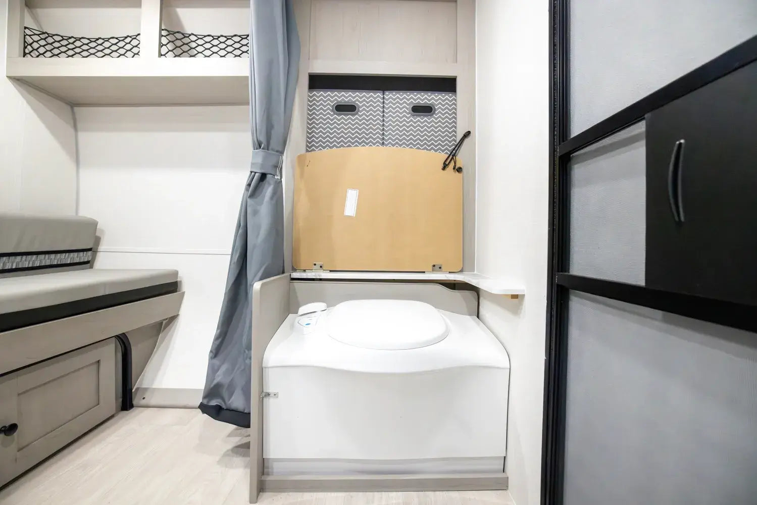 Compact bathroom with toilet, storage cabinet, and shower curtain in a small space.