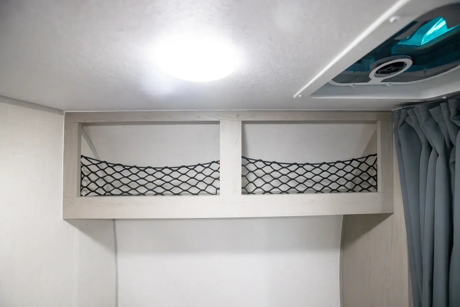 Ceiling storage compartment with a net divider in a vehicle interior.