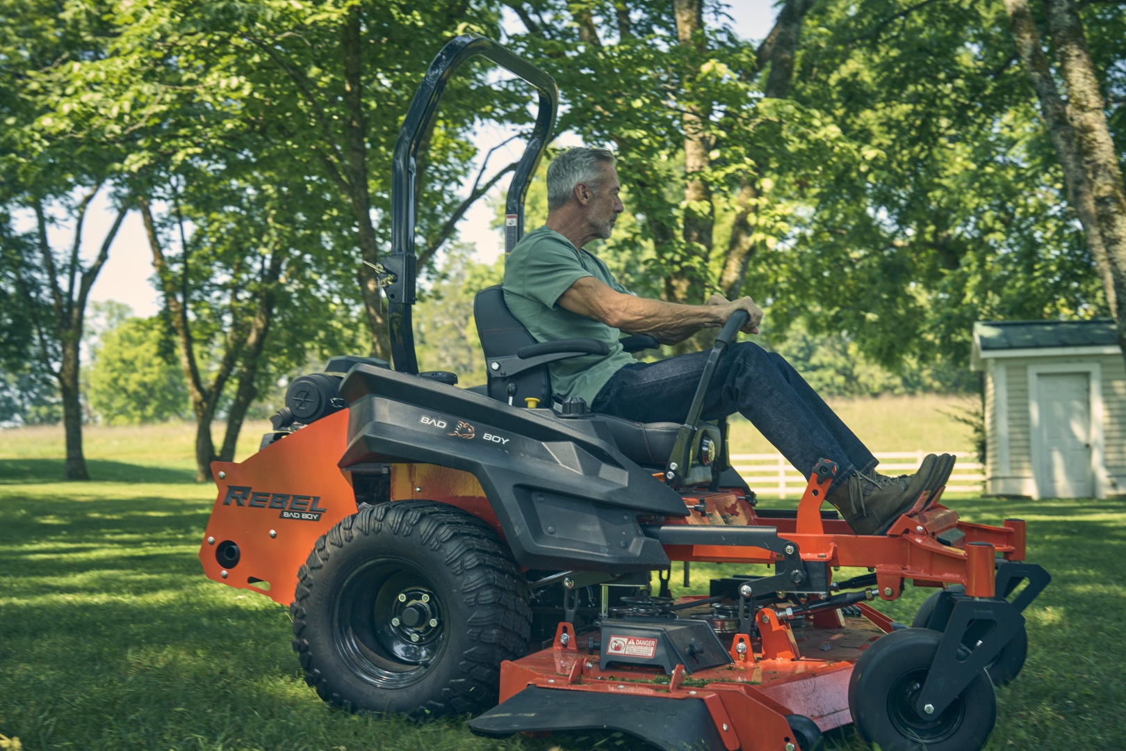 Man operating a riding lawn mower in a park setting