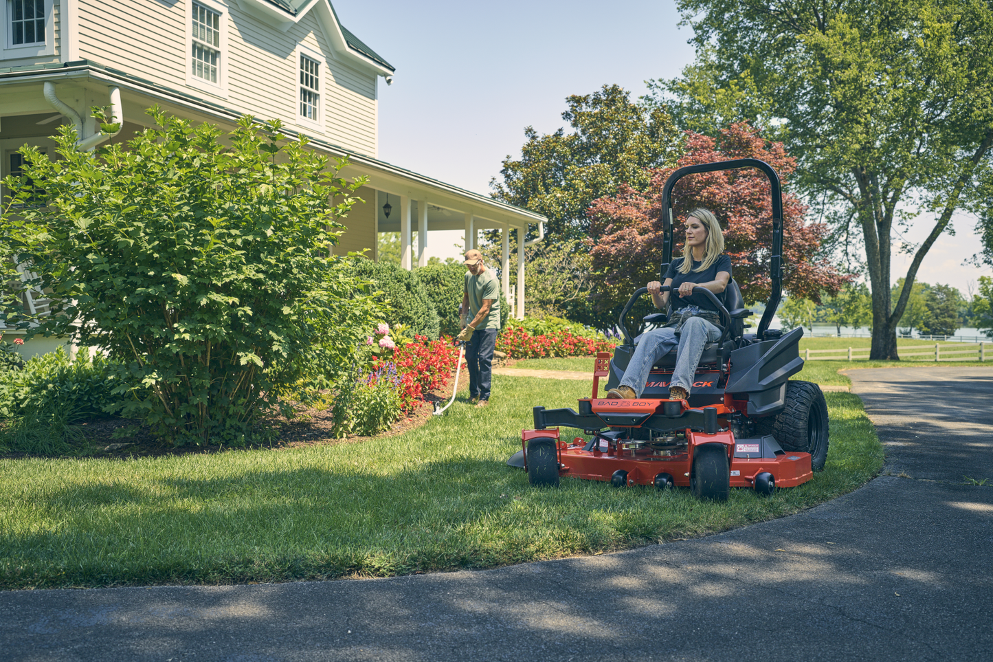 Person using a riding lawn mower in a residential driveway