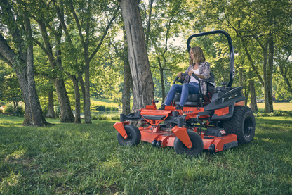 Person operating a red riding lawn mower in a park setting