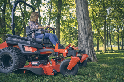 Person operating a red lawn mower in a park setting