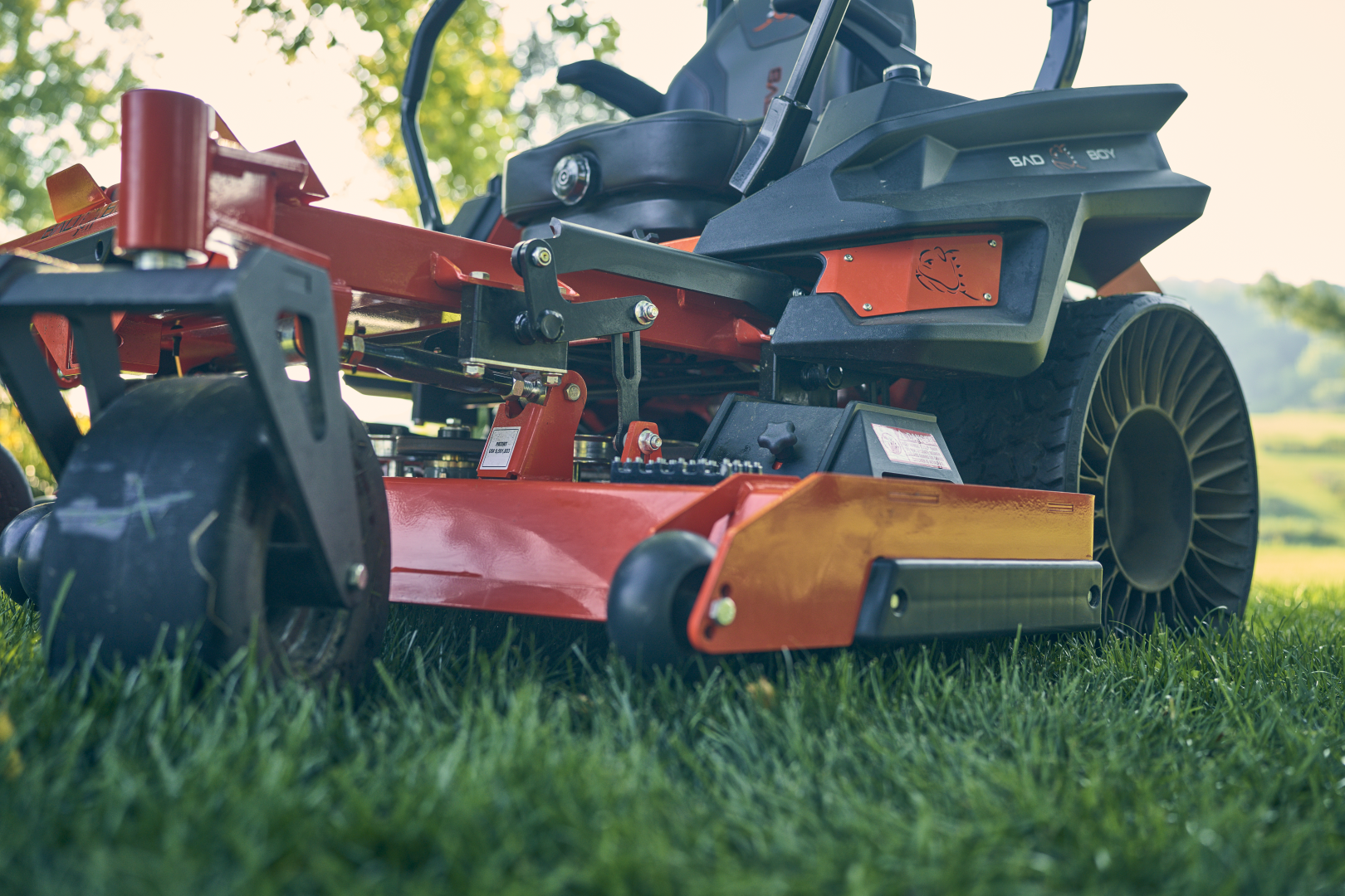 Red and black lawn mower on grass with blurred background