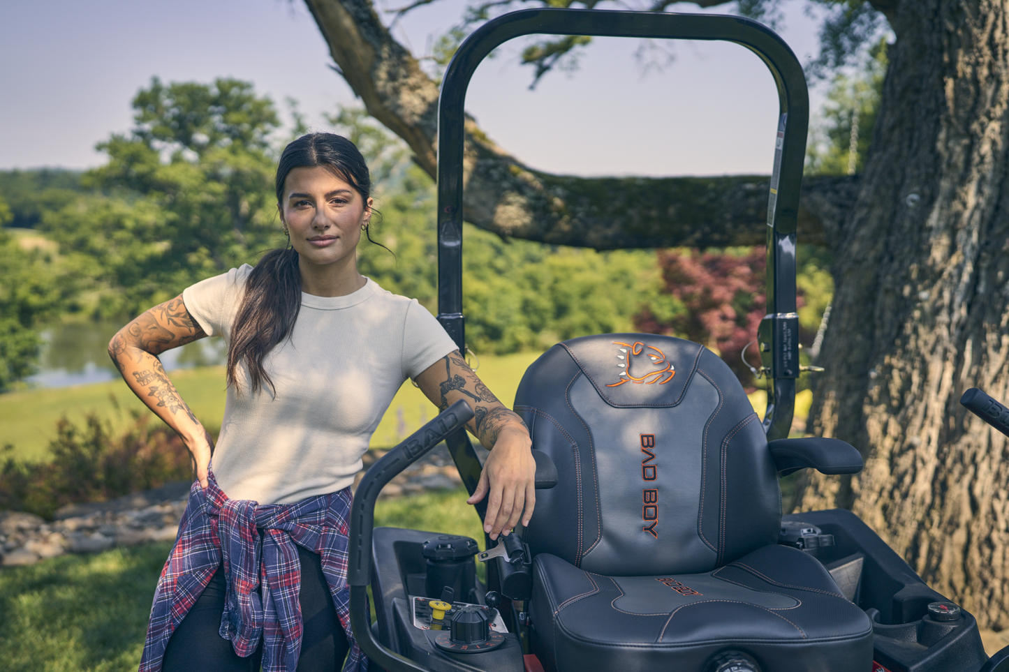 Woman standing next to a zero-turn mower in a scenic outdoor setting