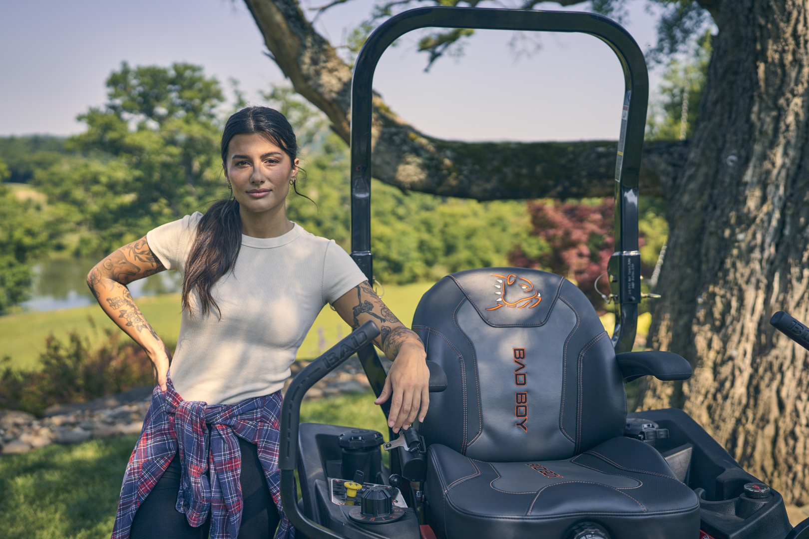 Woman standing next to a zero-turn mower in a scenic outdoor setting