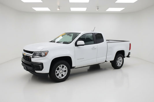 White pickup truck parked in front of a building with a gray sky.