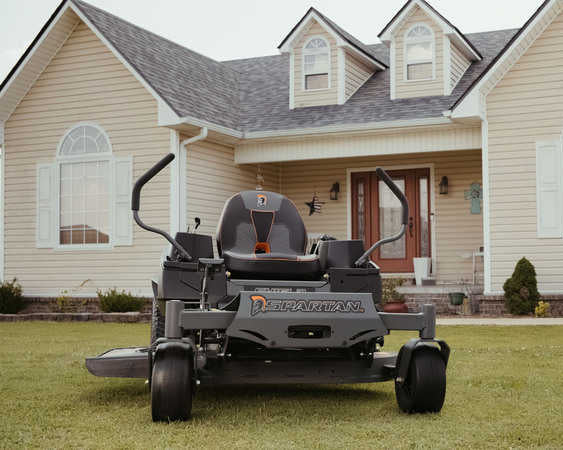 Zero-turn lawn mower in front of a house with a well-maintained lawn.