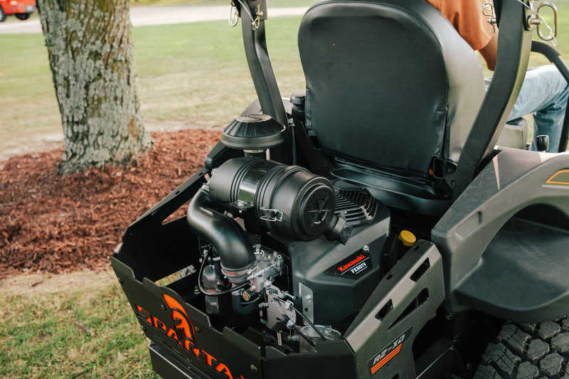 Close-up of a lawn mower engine with a person partially visible in the background.