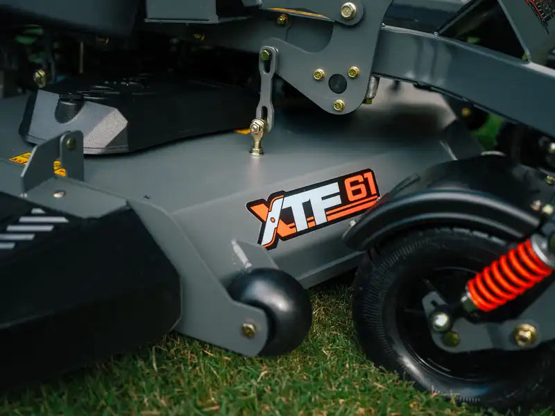Close-up of a lawn mower with 'XTF 61' branding on grass.