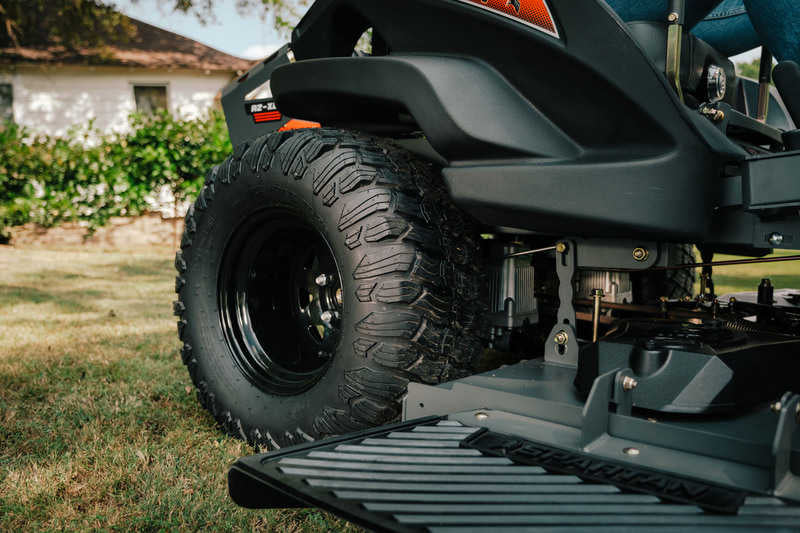 Close-up of a lawn mower with a large tire on grass
