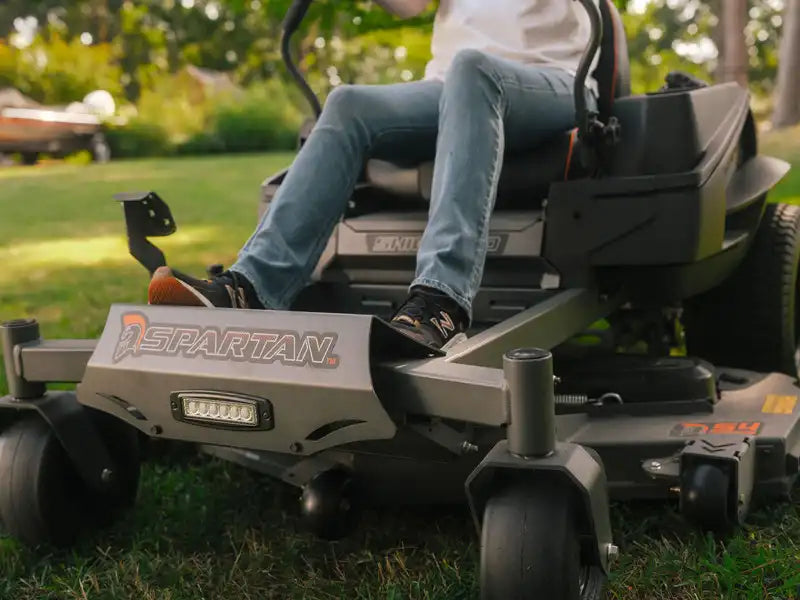 Person operating a Spartan riding lawn mower on grass