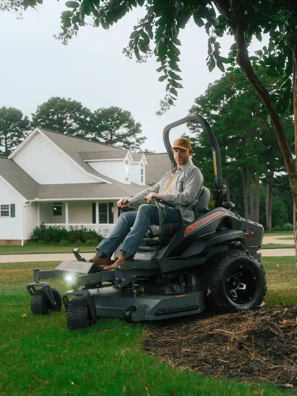Man operating a zero-turn lawn mower in a residential yard