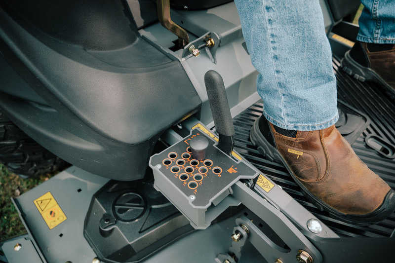 Close-up of a person operating a lawn mower with a control panel.