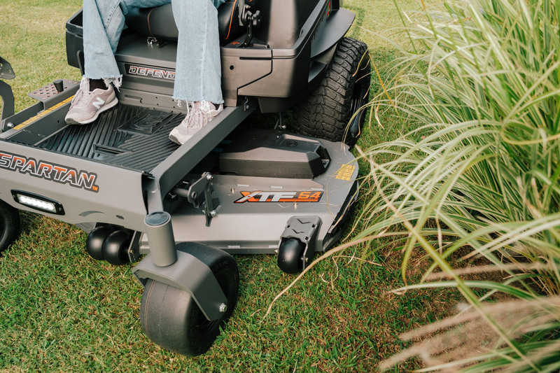 Person operating a Spartan riding lawn mower on grass
