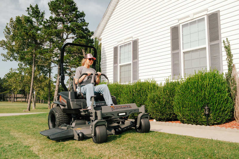 Person operating a riding lawn mower in front of a house