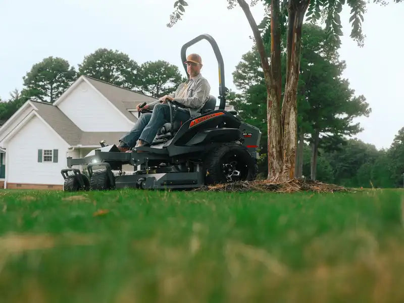 Person operating a zero-turn lawn mower in a residential area