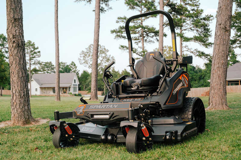 Zero-turn lawn mower on a grassy area with trees and houses in the background