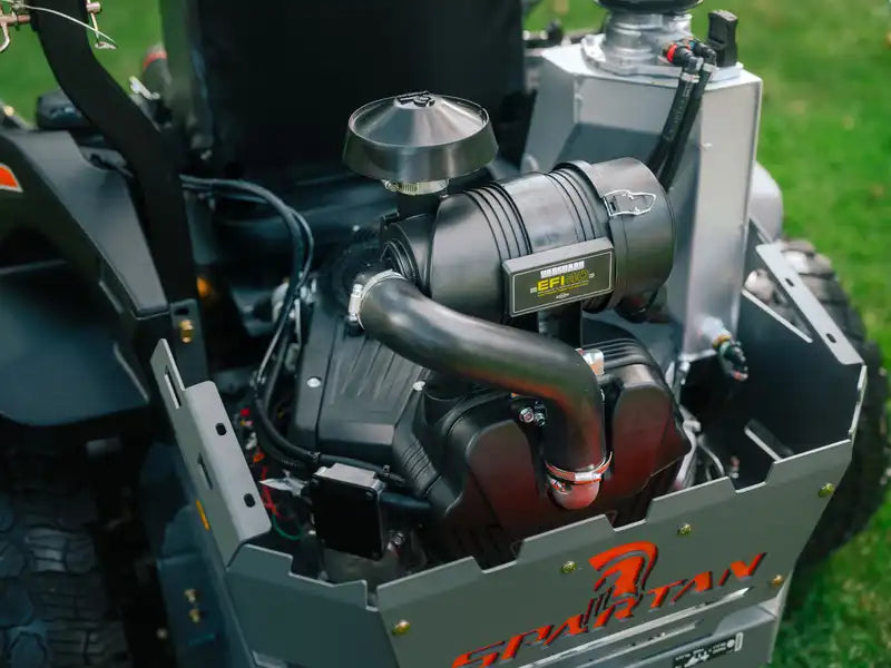 Close-up of a Spartan lawn mower engine with visible branding on a grassy background