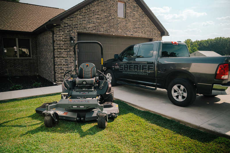 Mower and sheriff's truck in front of a house
