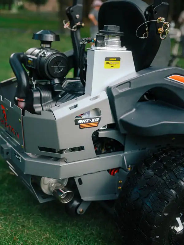 Close-up of a lawn mower engine with 'SRT-XG' branding on a grassy background.