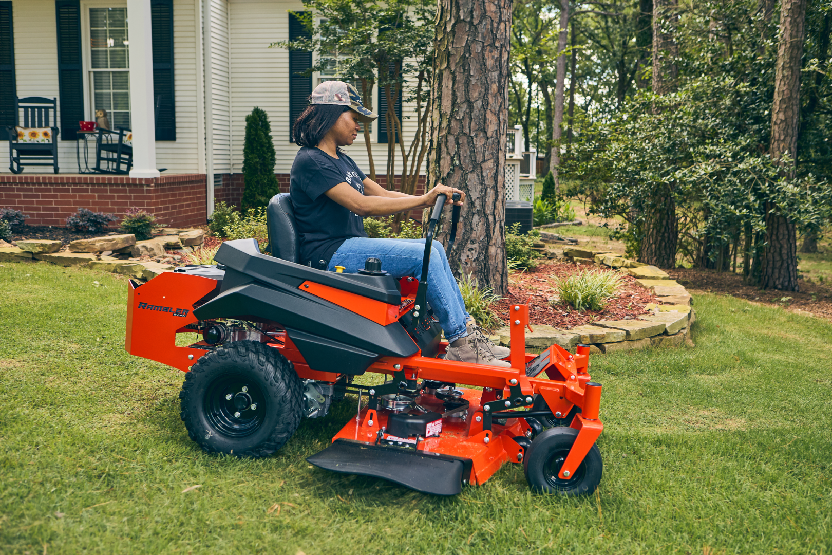 Person operating a red riding lawn mower in a garden setting