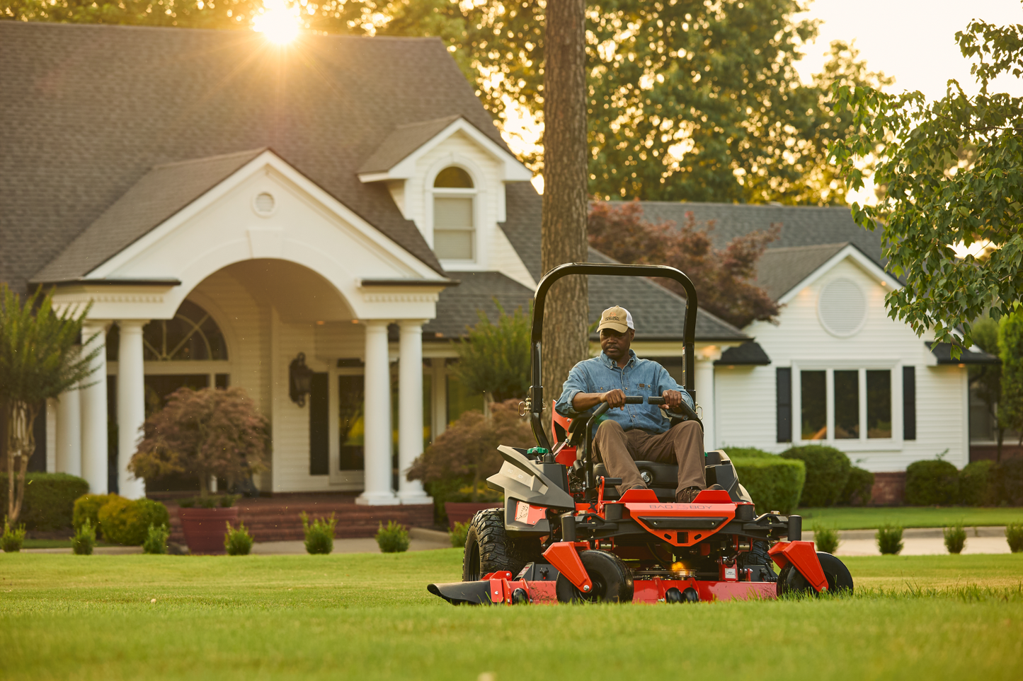 Man operating a lawn mower in front of a house