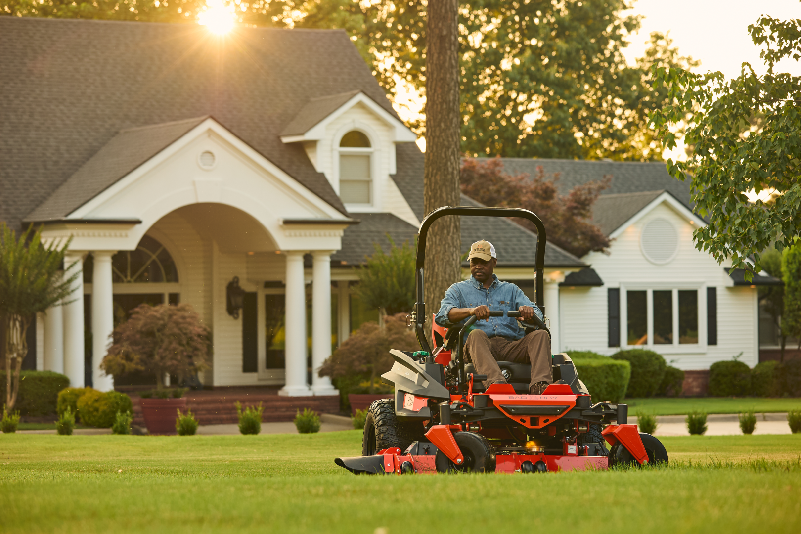 Man operating a lawn mower in front of a house