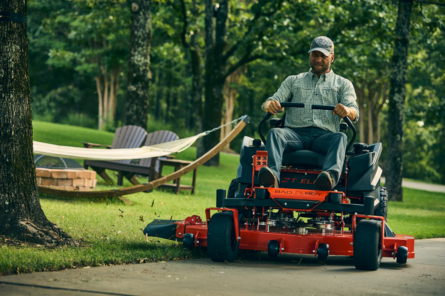 Man operating a red riding lawn mower in a park setting