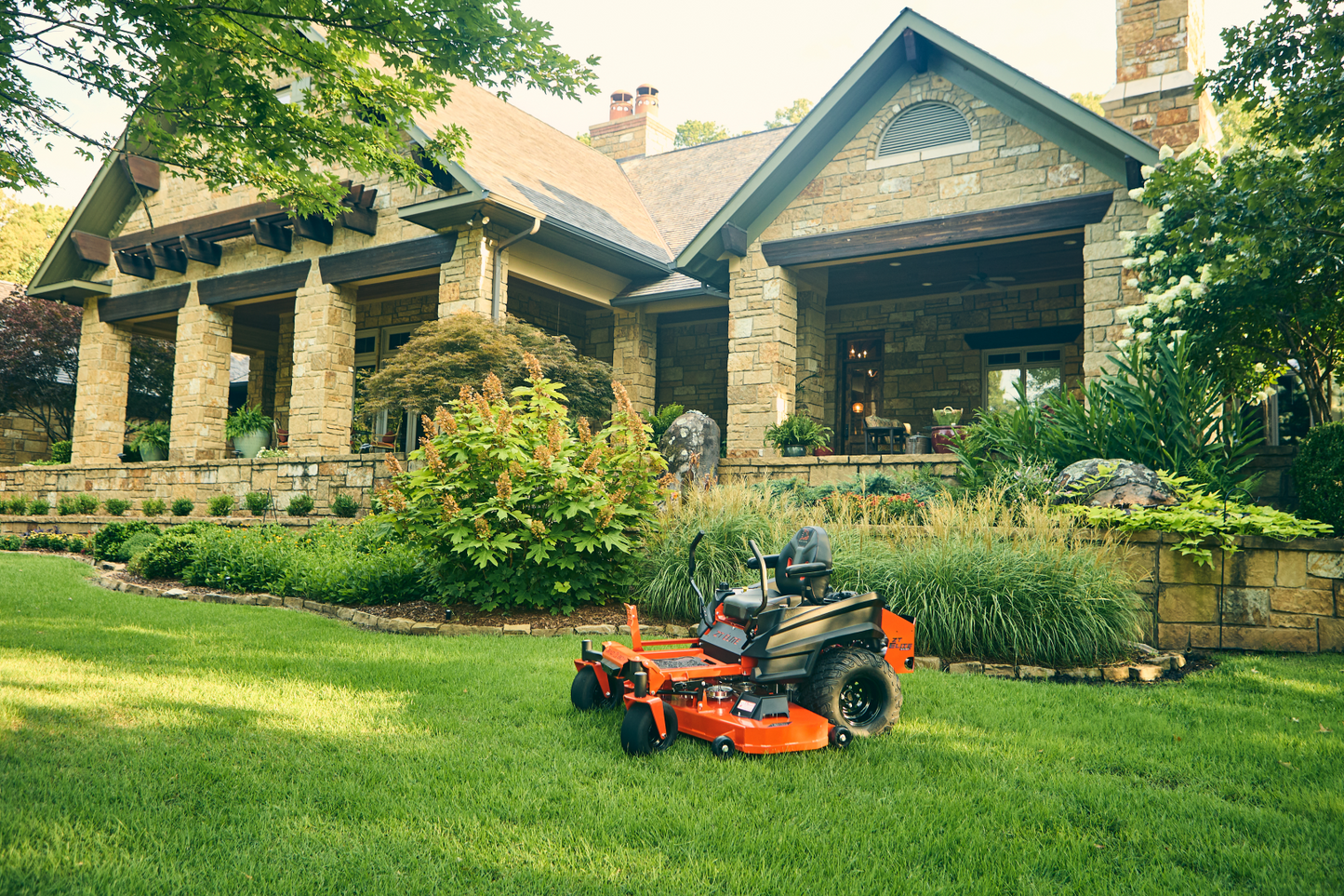 Orange lawn mower on a well-maintained lawn in front of a house.