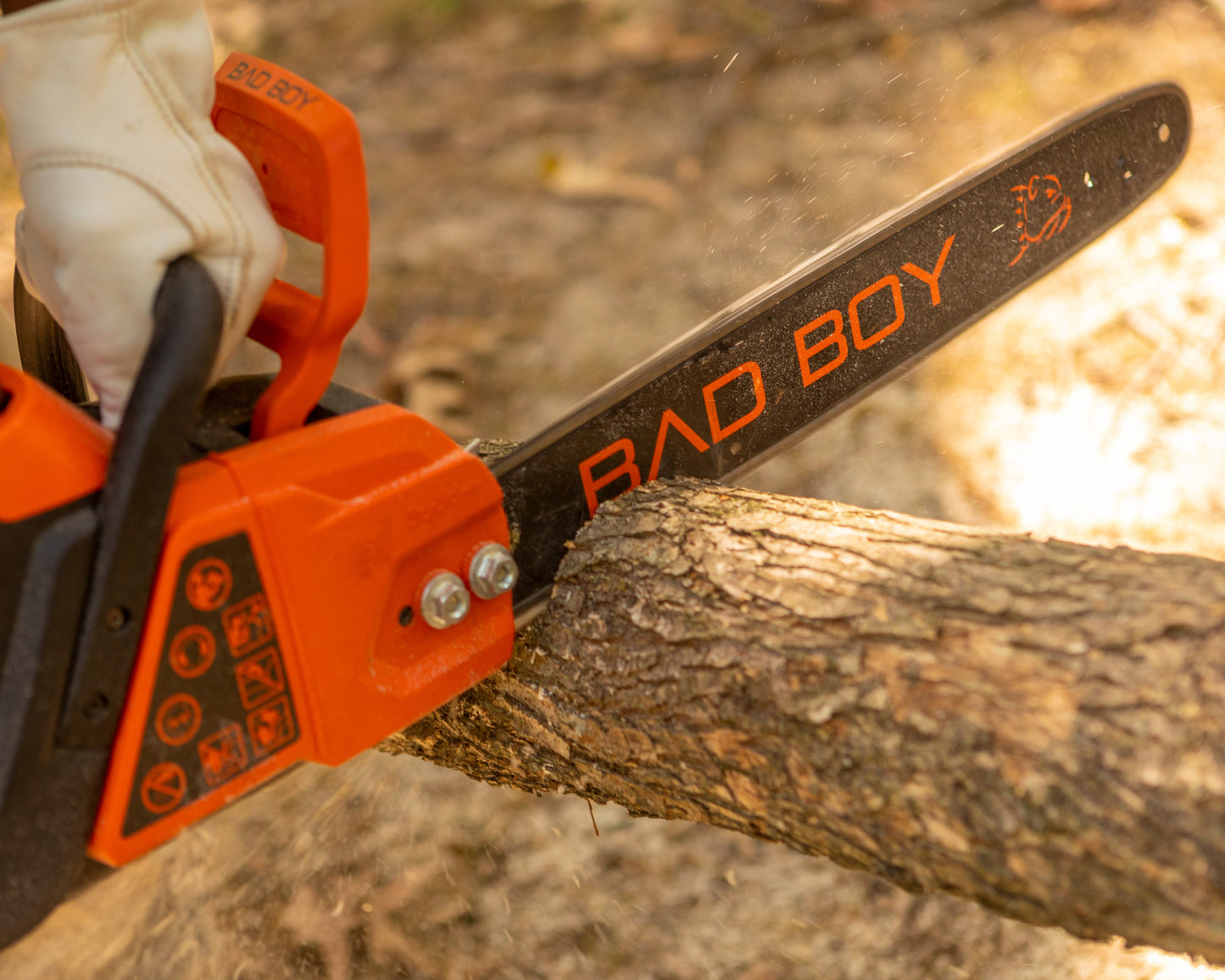 Person using a chainsaw with 'Bad Boy' branding to cut a tree branch.