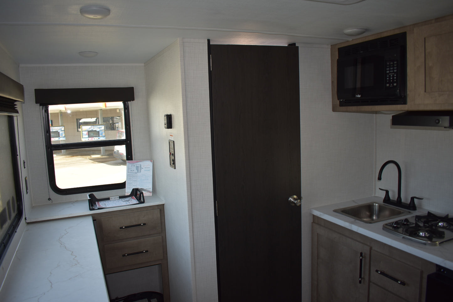 Small kitchen inside a vehicle with cabinets, sink, and microwave.