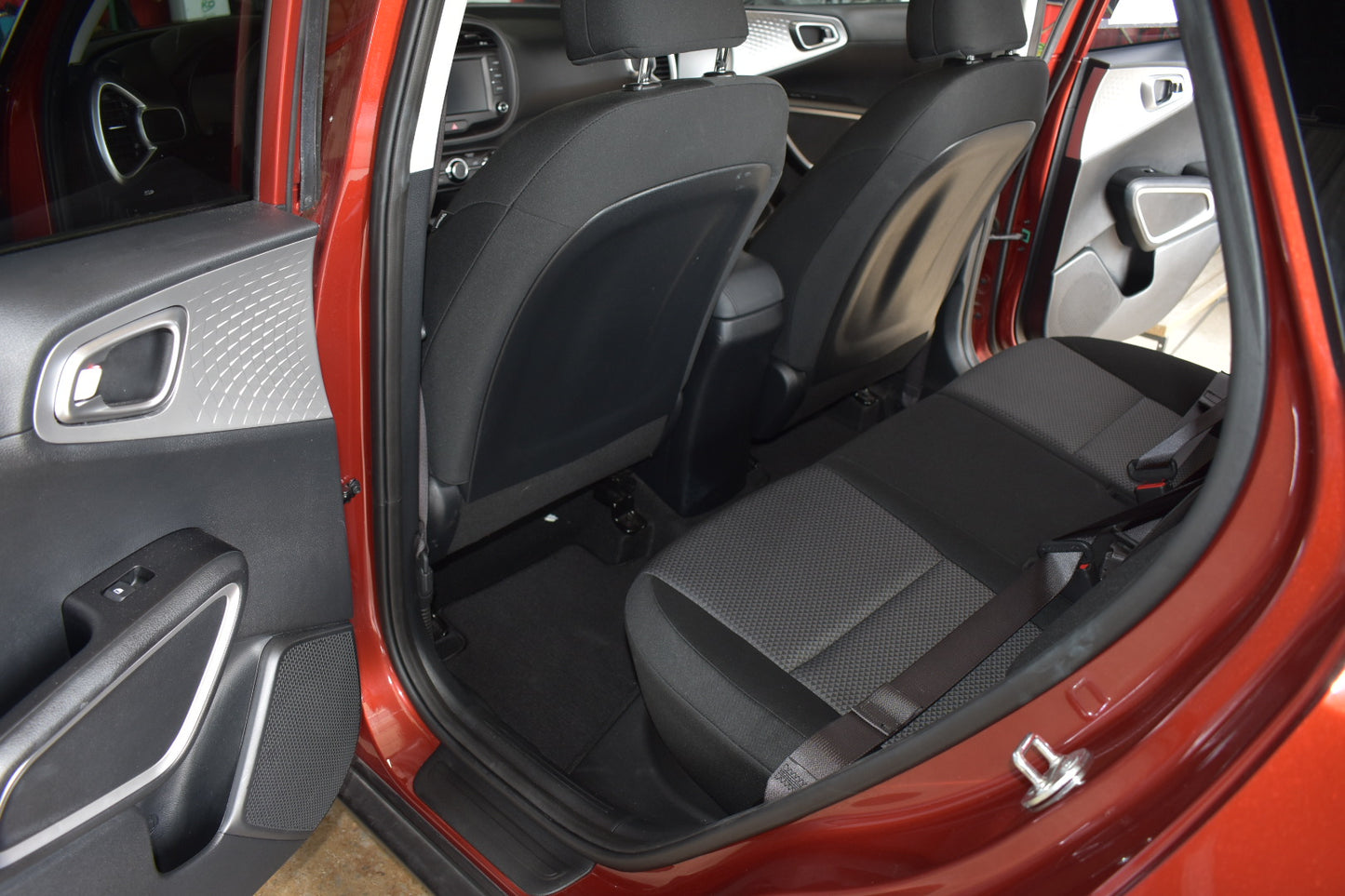 Open car door showing interior with gray seats and red car exterior