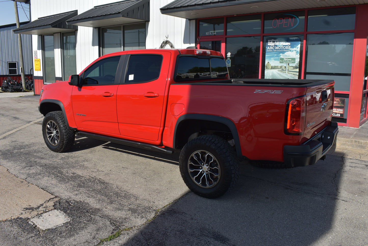 Red pickup truck parked in front of a building with large windows.