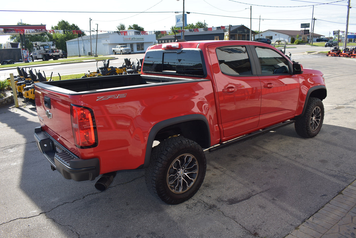 Red pickup truck parked on a paved surface with a cityscape in the background