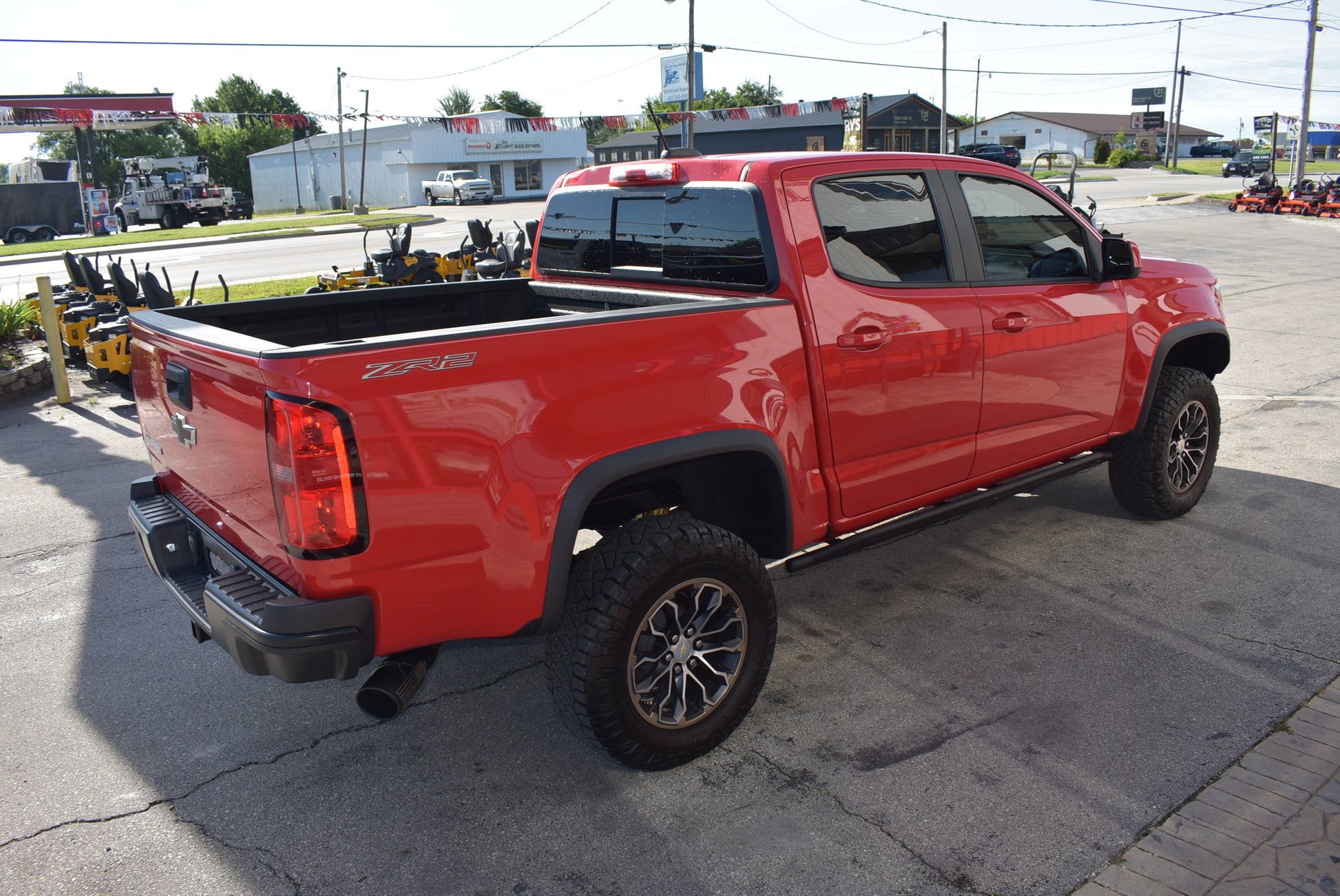 Red pickup truck parked on a paved surface with a cityscape in the background