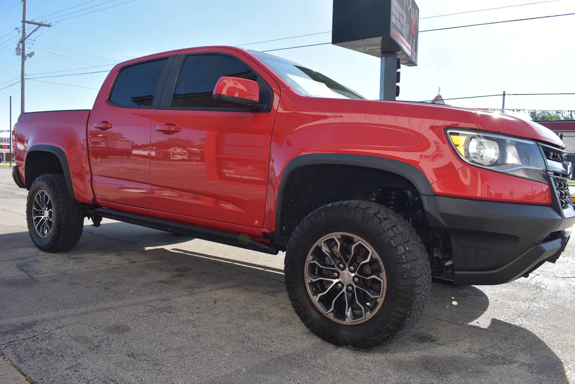 Red pickup truck with large tires on a paved surface