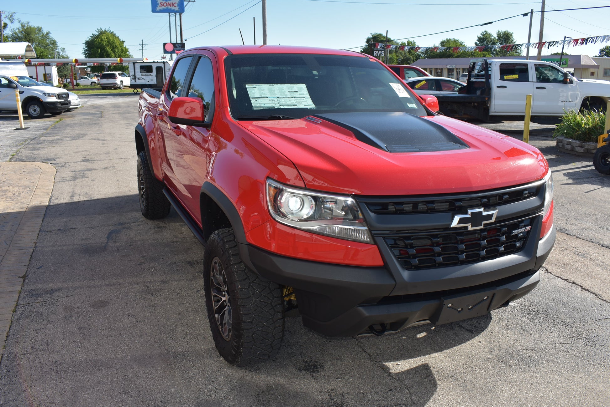 Red Chevrolet truck parked on a lot with other vehicles in the background
