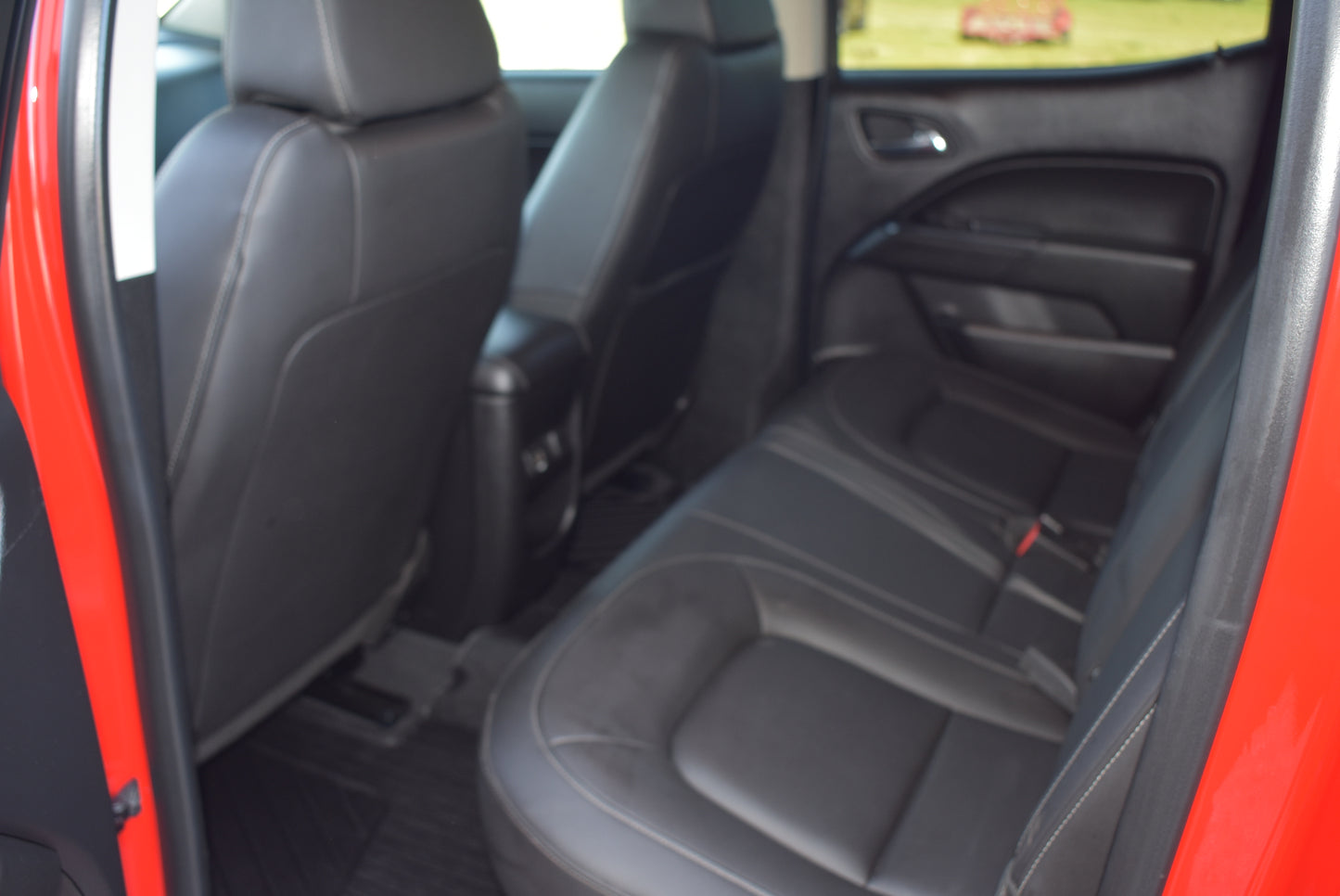 Back seat of a car with open door, showing interior details.